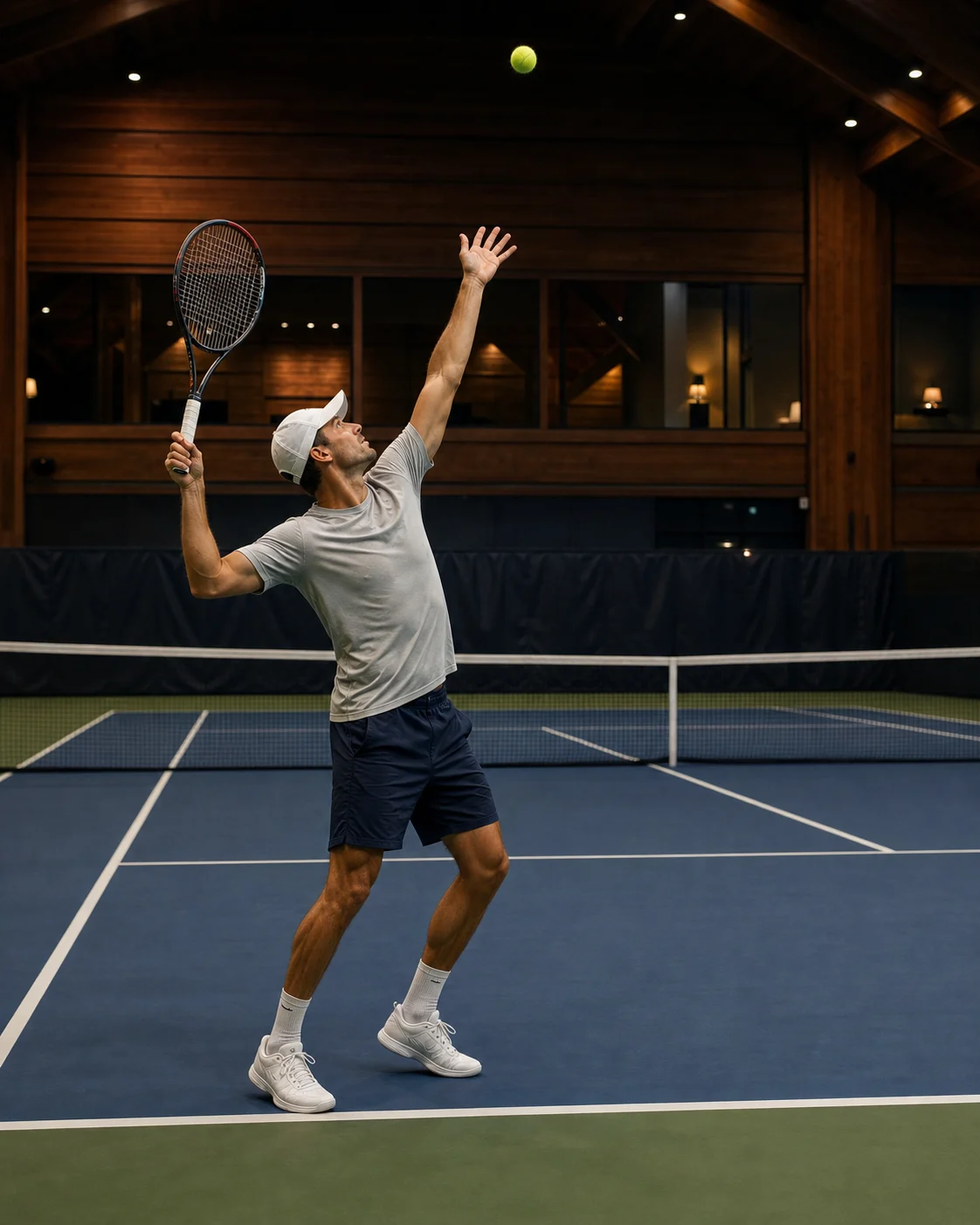 Tennis player serving on an indoor court