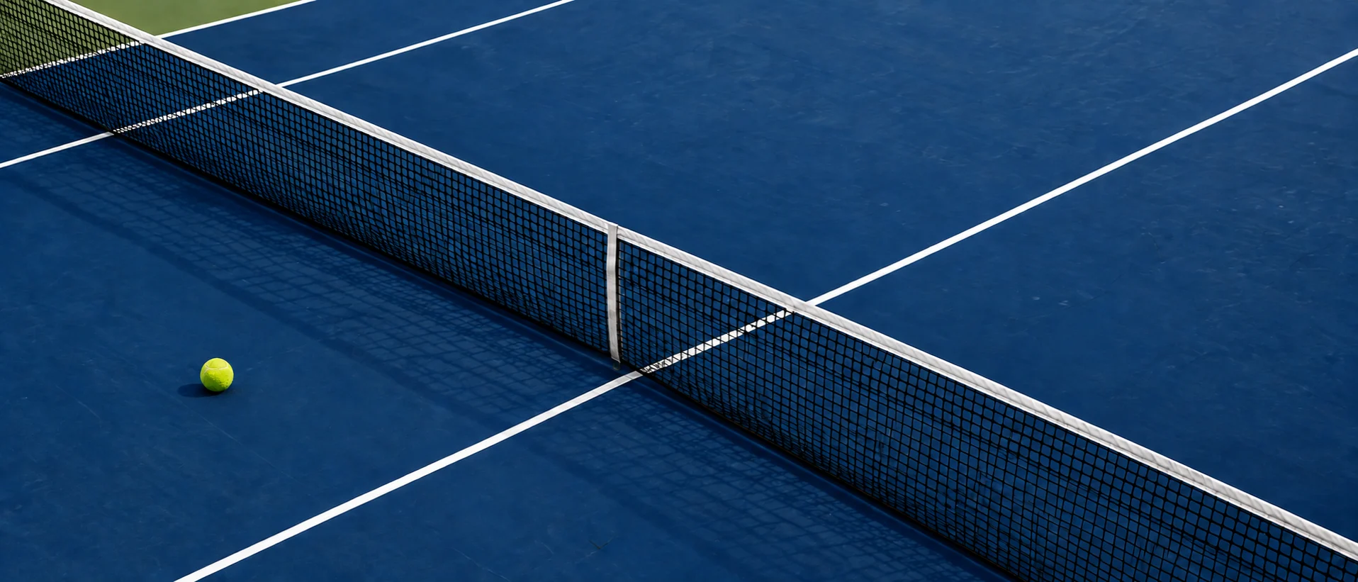 Tennis ball beside the net on a blue court